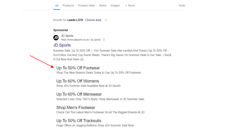 A Google search engine results page features a sponsored ad from JD Sports, with black sitelinks showing steep discounts: up to 50% off on footwear, 60% off on women's clothing, and 50% off on menswear. A red arrow draws attention to the testing of the fantastic footwear offer.