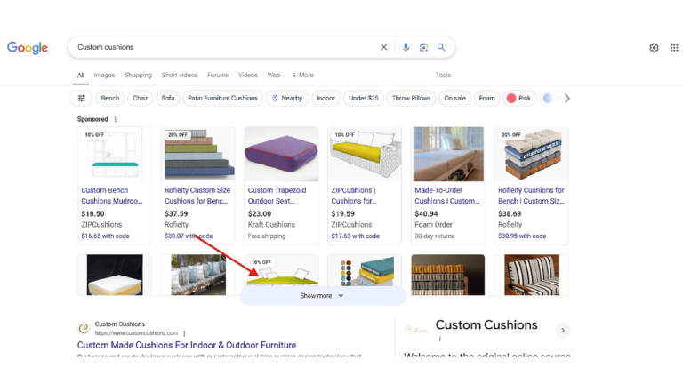 The Google search results page for "Custom Cushions" displays make-to-order cushion products, complete with vibrant images and links. A red arrow directs your attention to the "Show More" button at the heart of the page, ensuring you don't miss any top SEO keywords or main search ads.