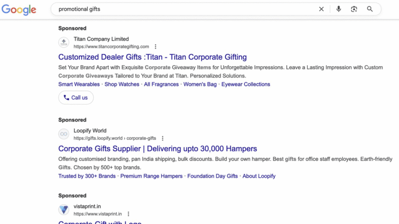 Google search results page for "promotional gifts," showing sponsored links for Titan Company, Loopify World, and Valueprint.in, each offering customized corporate gifting and hampers. The search bar appears at the top.