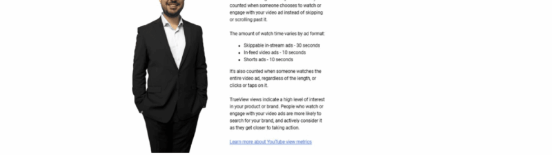 A man in a suit stands next to text explaining that Google Ads has renamed "Views" to "TrueView Views," with a large blue downward arrow above him and a red "NEW!" graphic beside the text.