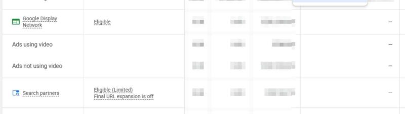 A Google Ads dashboard displays campaign channels, statuses, and metrics. The user opens the "Segment" dropdown, highlighting "Ads using video," utilizing the video usage segment for enhanced channel reporting. Data in columns is blurred for privacy.