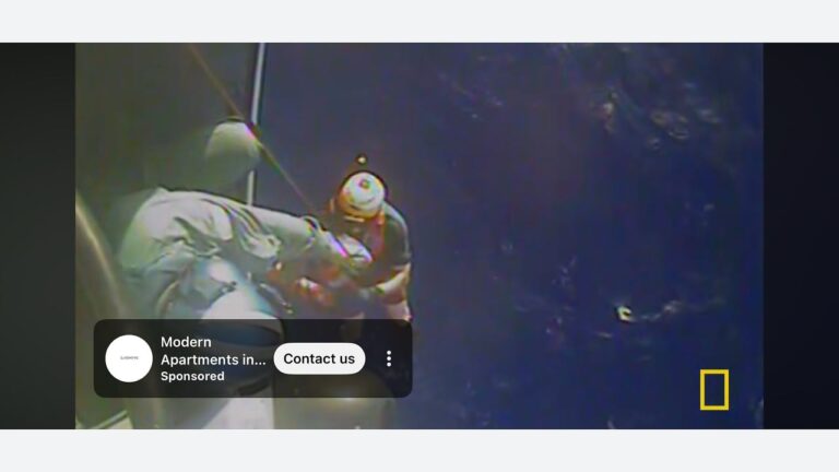 A rescue worker wearing a helmet hoists a person up from the ocean using a cable, with dark blue water below. A National Geographic logo appears in the corner, and an ad overlay is present at the bottom left.