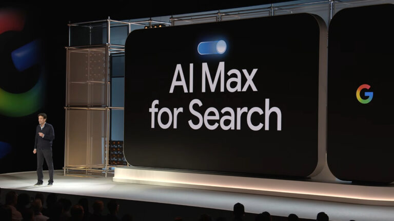A presenter stands on stage next to a large display screen showing "AI Max for Search" with the Google logo visible, announcing the global release of Google's AI Max search feature.