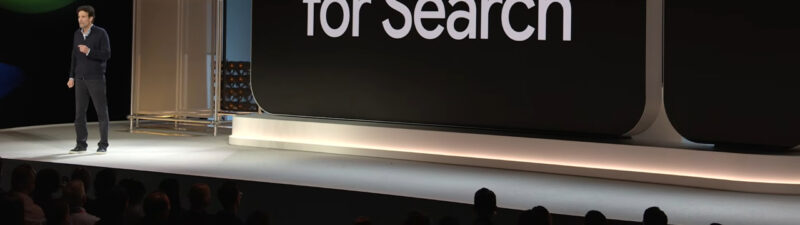 A presenter stands on stage next to a large display screen showing "AI Max for Search" with the Google logo visible, announcing the global release of Google's AI Max search feature.
