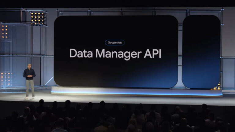 Speaker presenting Google Ads Data Manager API on stage at a conference with large display screen and audience in foreground
