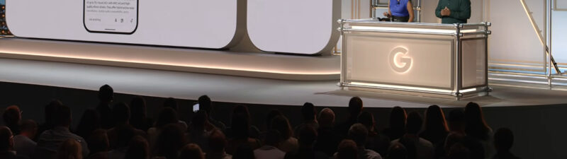 Google Search presentation on stage showing ads in AI Mode feature with shopping products displayed on large screens and two presenters at podium