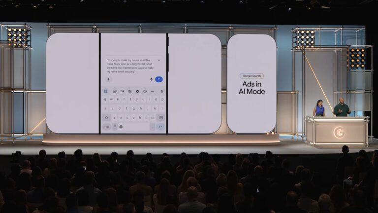 Large stage presentation screen showing Google Search interface with "Ads in AI Mode" display, featuring a search query about home scents and a virtual keyboard, with audience members visible in foreground and two presenters at a desk on the right side.