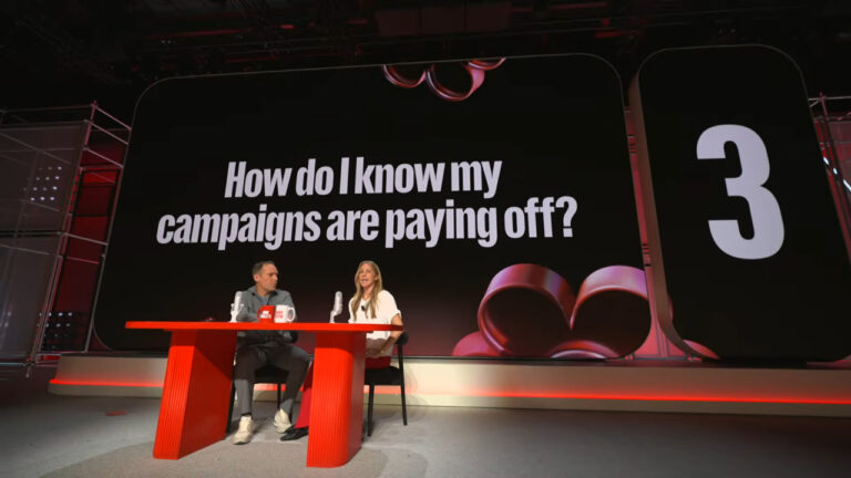 Two panelists discuss campaign measurement at a marketing conference, with a large screen displaying the question "How do I know my campaigns are paying off?" and the number 3 visible on the right side.