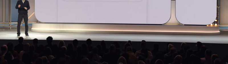 Google Search interface displayed on large presentation screen showing a query about pottery hobbies with AI Mode options and send button visible, presenter standing on stage in front of audience