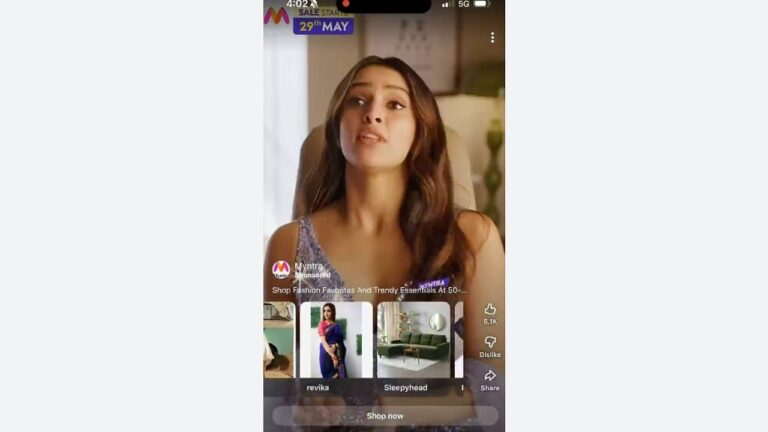 A woman with long brown hair sits in a light-colored chair, looking upward. The screen shows a Myntra app advertisement with clothing and home decor items, user engagement icons, and text about a sale starting May 29th.