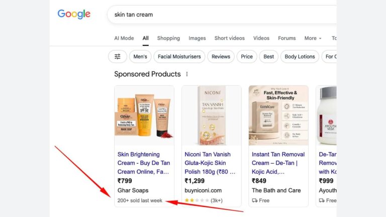 Screenshot of Google search results for “skin tan cream,” showing sponsored product listings with prices, ratings, and product images. A red arrow points to “200+ sold last week” under the first product listing.
