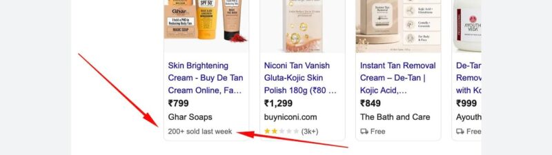 Screenshot of Google search results for “skin tan cream,” showing sponsored product listings with prices, ratings, and product images. A red arrow points to “200+ sold last week” under the first product listing.